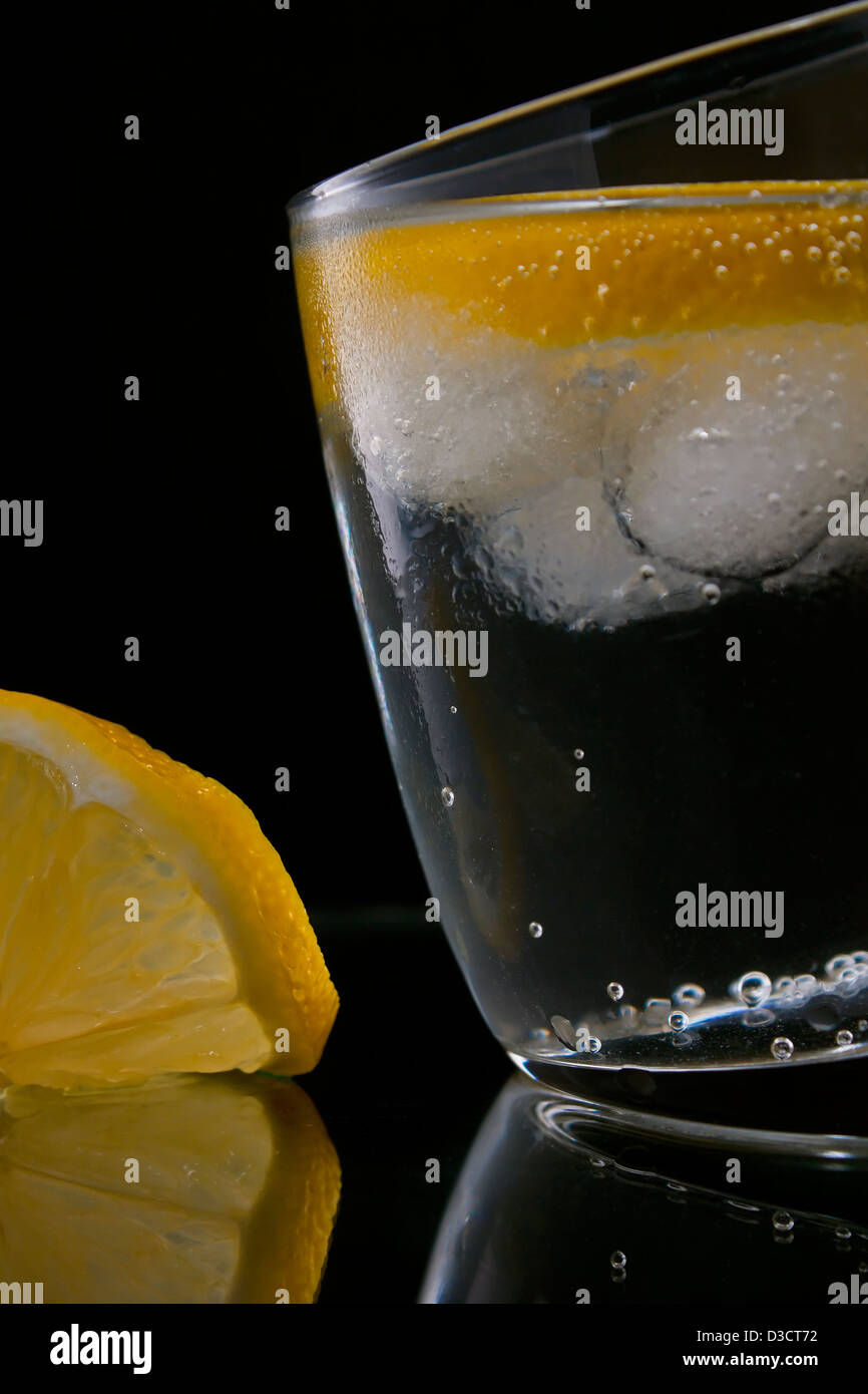 Gin and tonic or vodka and tonic with a slice of lemon over black Stock