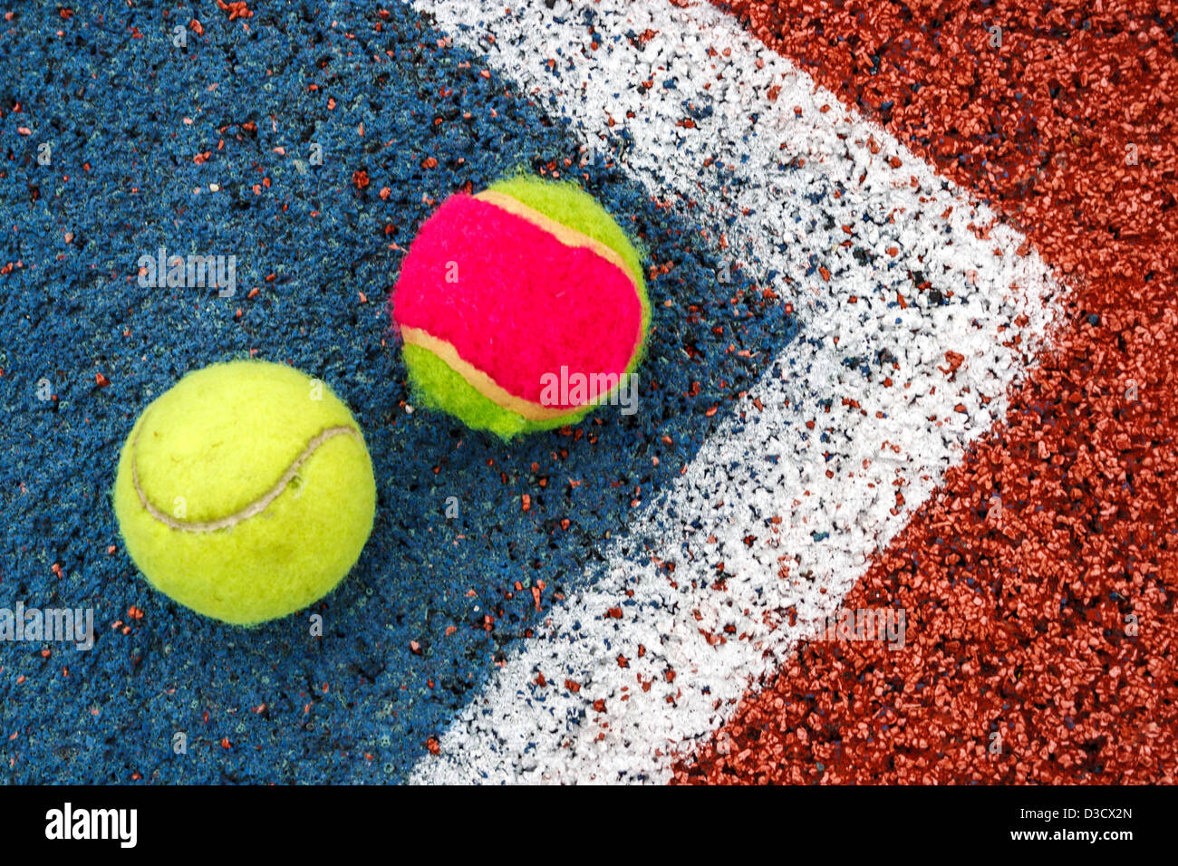 Tennis colored balls placed in the corner of a synthetic field. Stock Photo