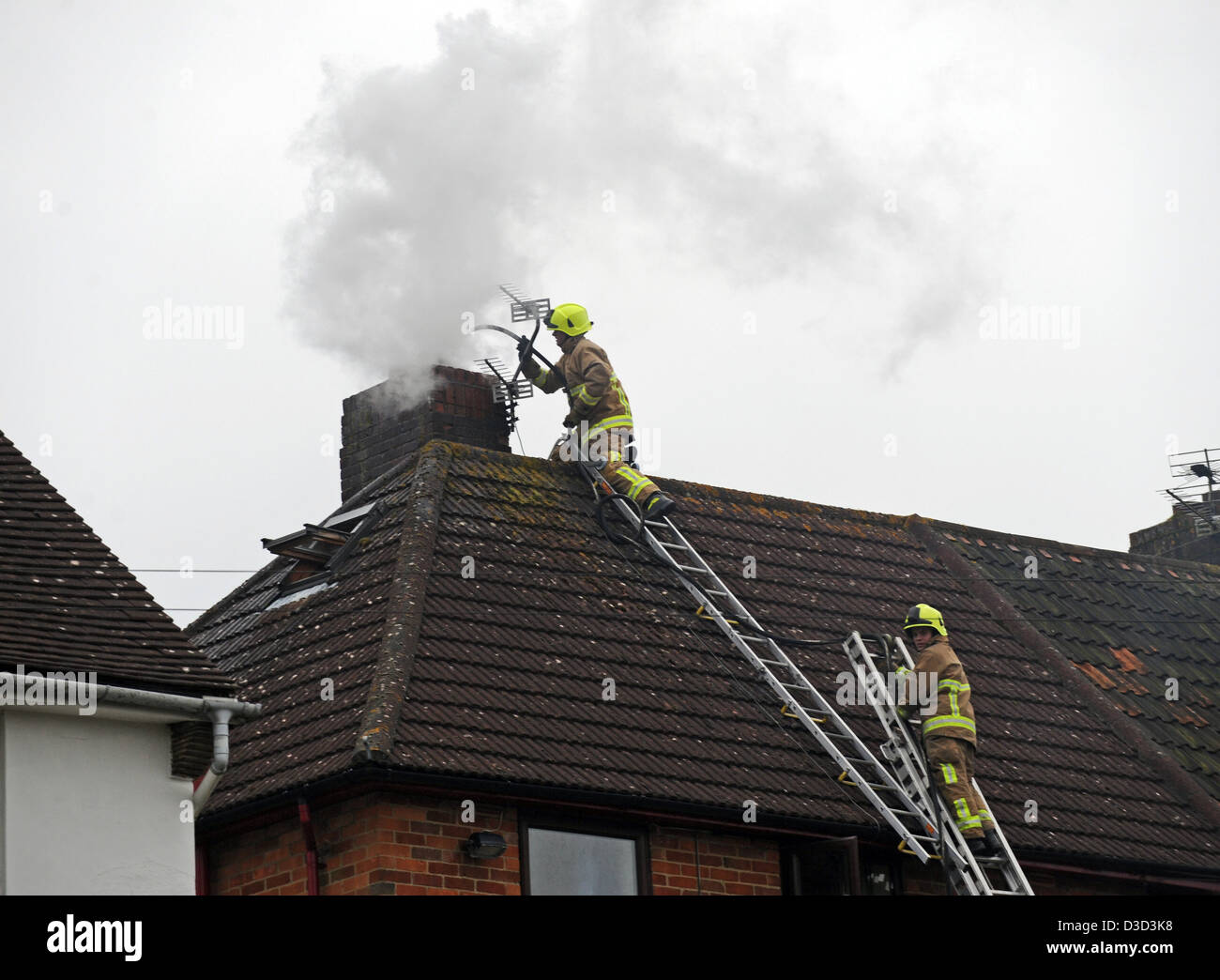 Firefighters dealing with a chimney fire on the roof of a house in