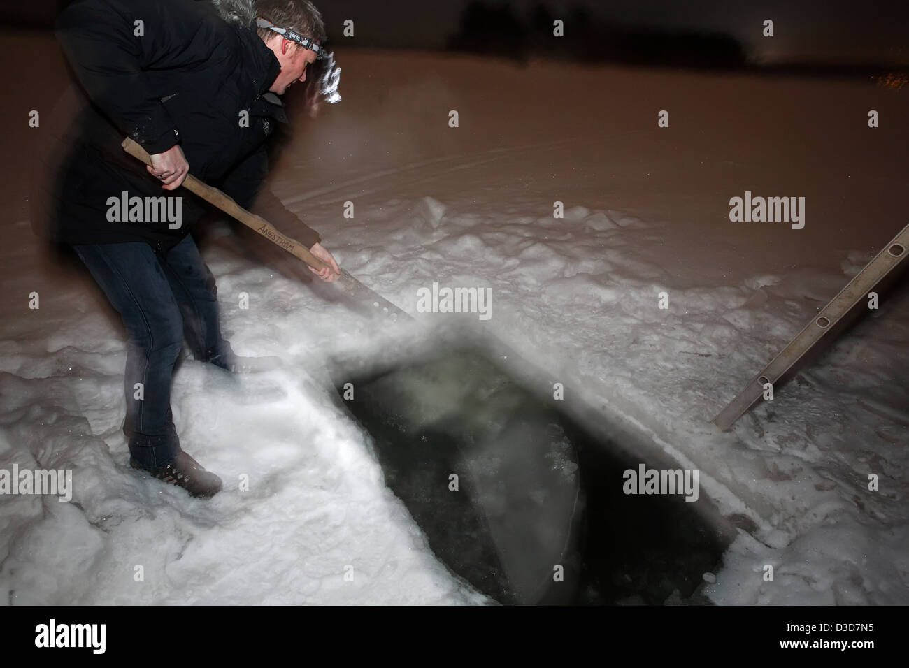 Dill, Sweden, a man opens a Eissaege again the frozen swimming hole Stock Photo