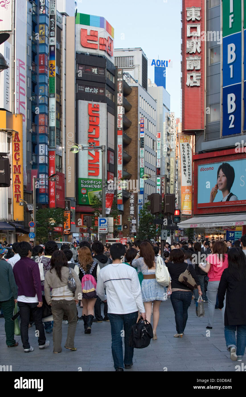 A typical busy downtown Shinjuku, Tokyo street during mid-day with a skyline of buildings and signs towering overhead. Stock Photo