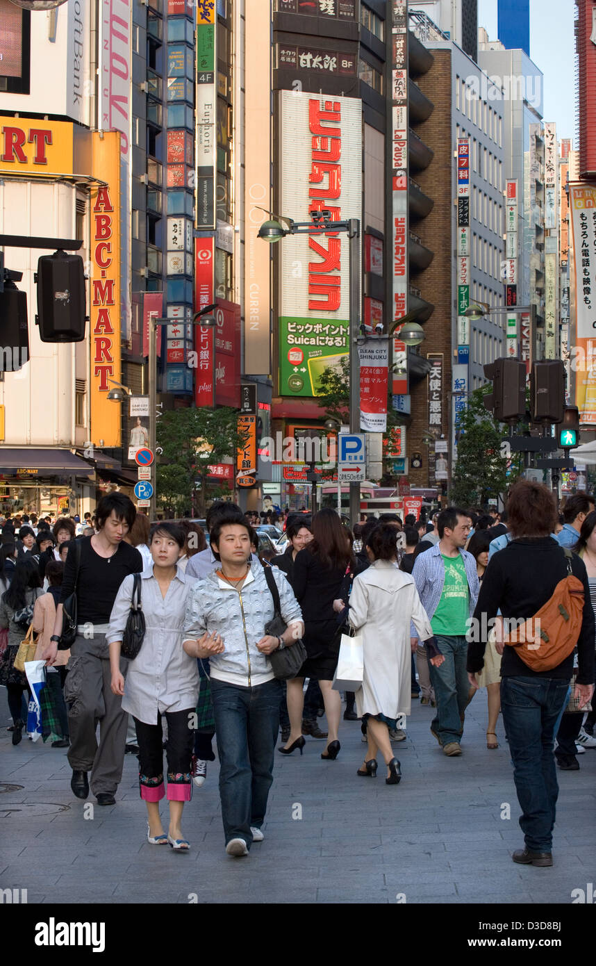 A busy downtown Shinjuku, Tokyo street during early evening with a skyline of buildings and signs towering overhead. Stock Photo