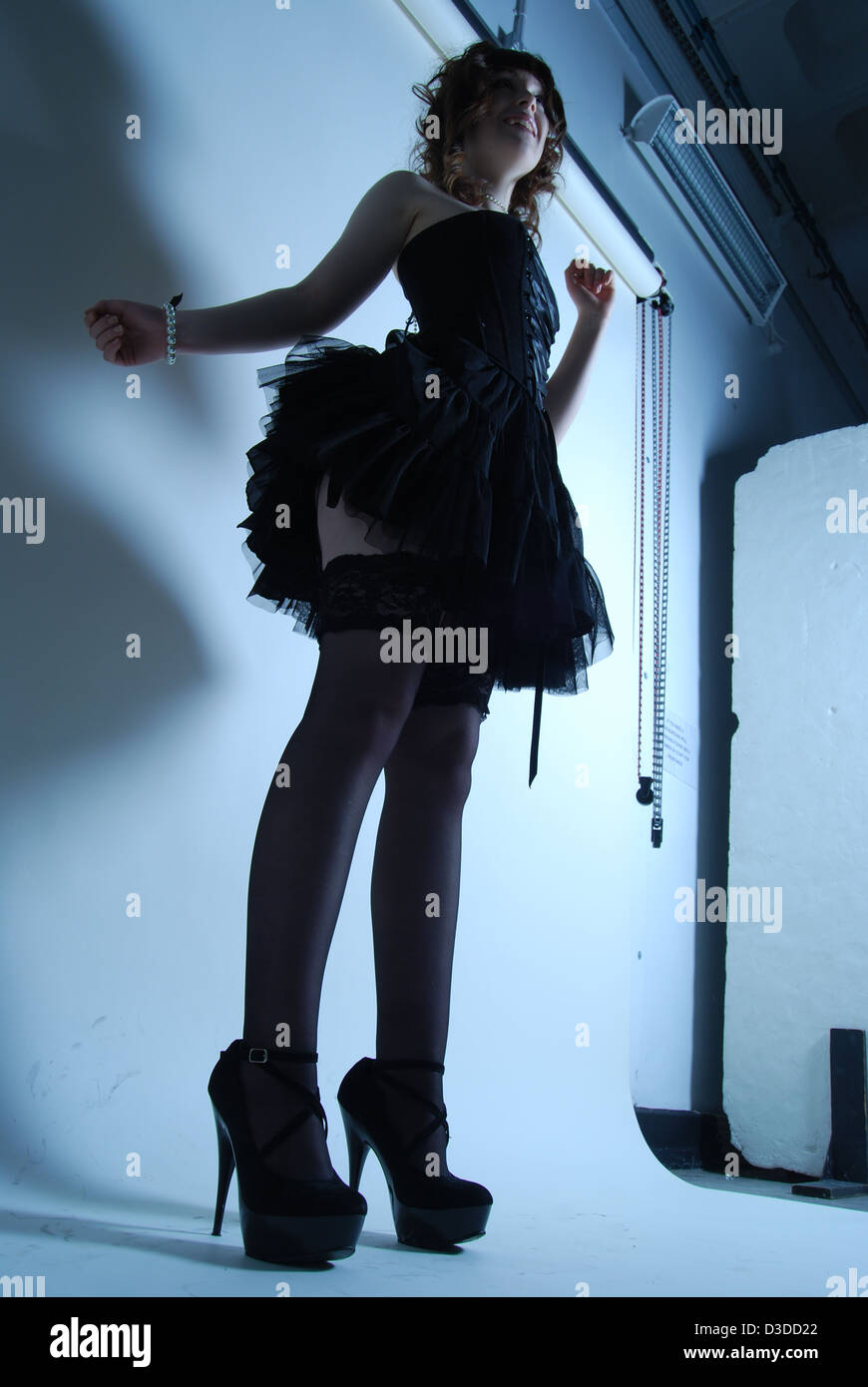 Tall model silhouette of a female in a studio setting with background in  short black dress posing with high heels for fashion Stock Photo - Alamy