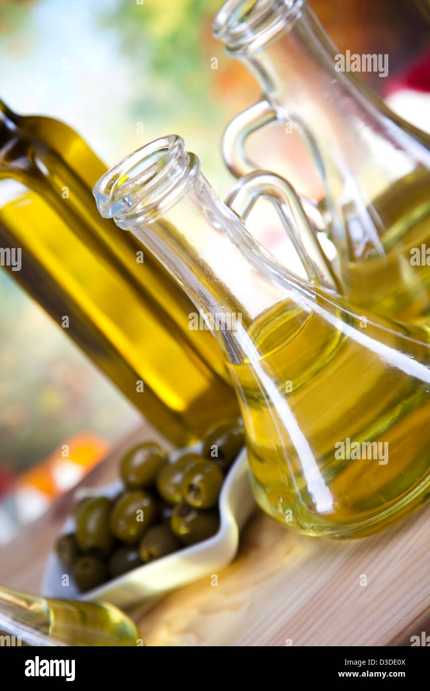 Glass bottle of premium virgin olive oil and some olives with leaves ...