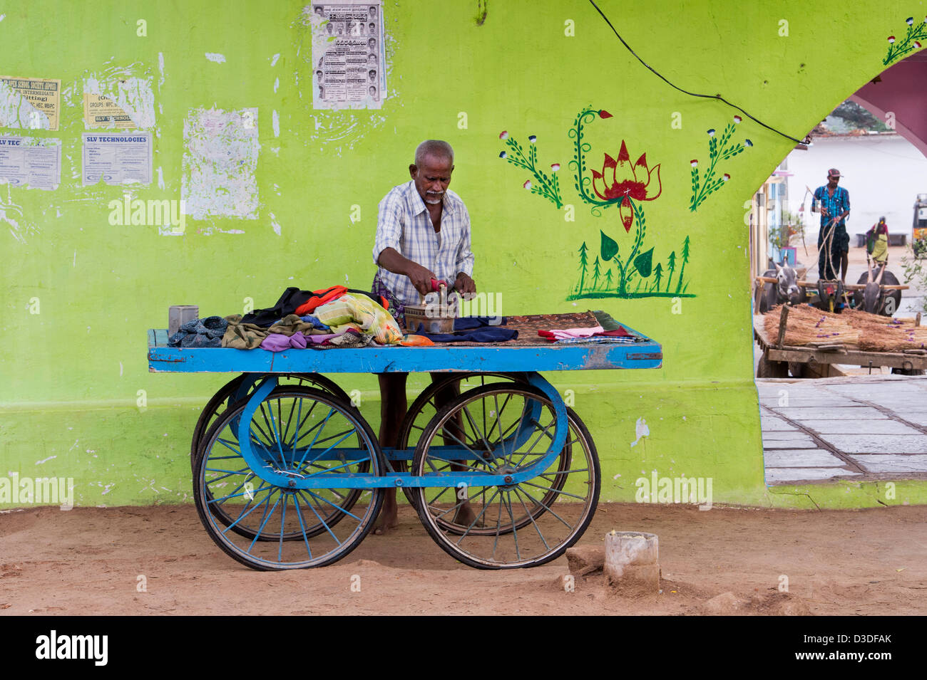 Traditional Indian street laundry man (dhobi) ironing washed clothes on a cart. Andhra Pradesh, India Stock Photo