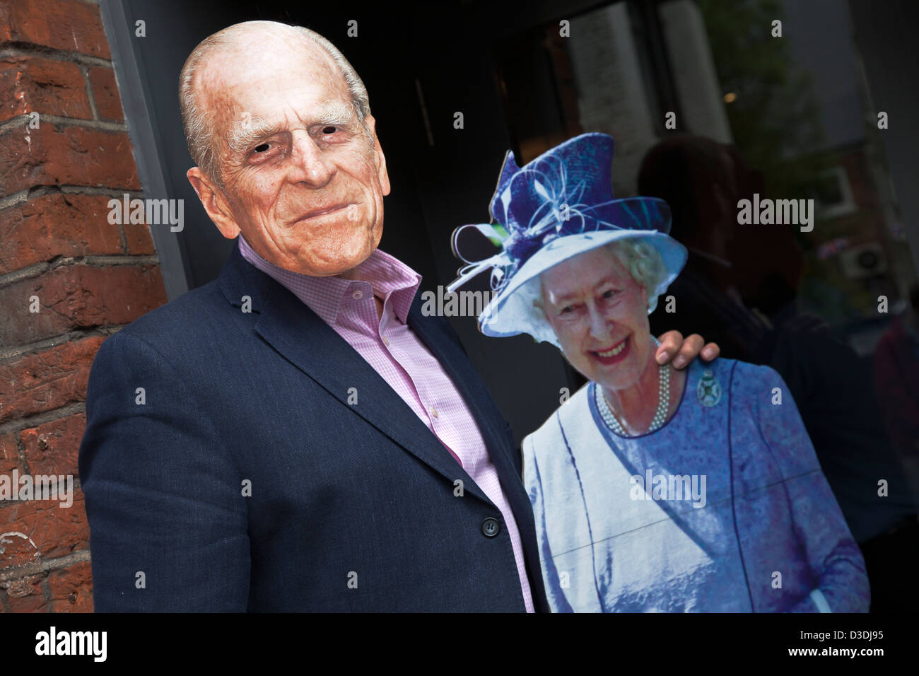 Cut out of Queen Elisabeth II and a man wearing Prince Philip mask in a Chiswick restaurant, London, UK Stock Photo