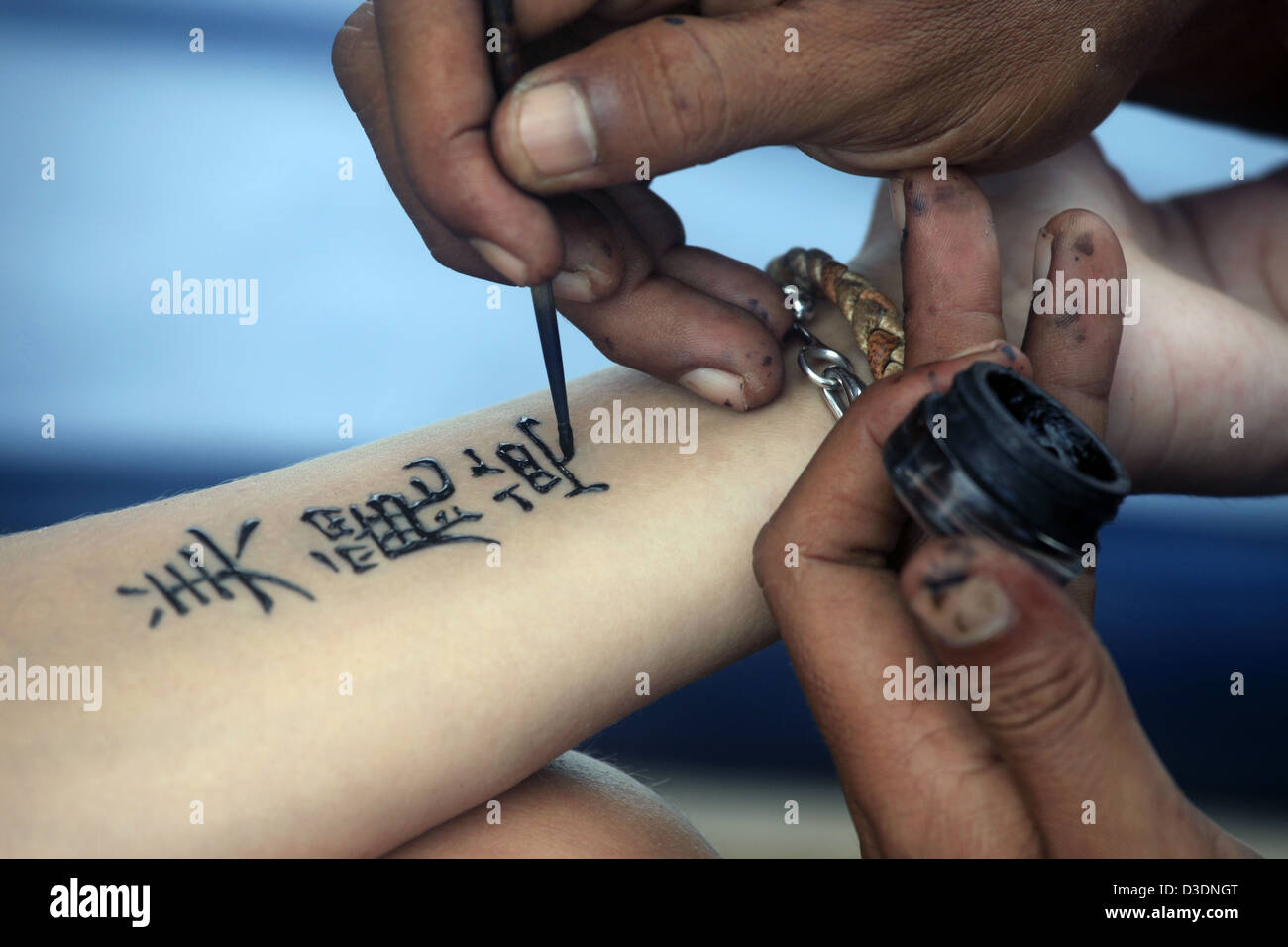 Artist draws a tattoo henna on a female hand. Hieroglyph Artist draws a tattoo henna on a female hand. Hieroglyph