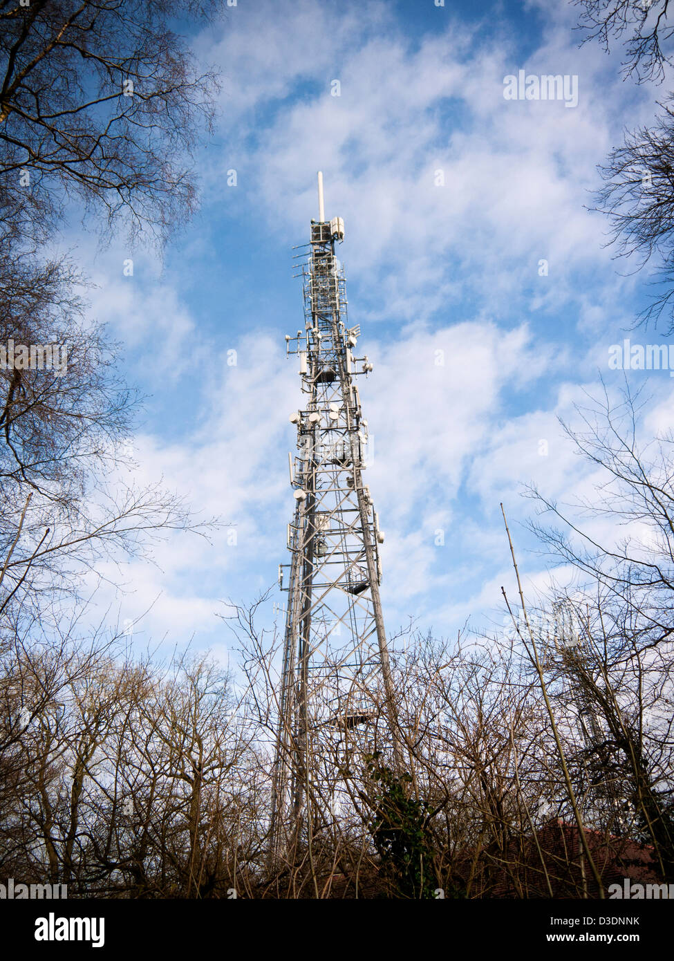 Communications tower with many aerials and dishes against a blue sky Stock Photo