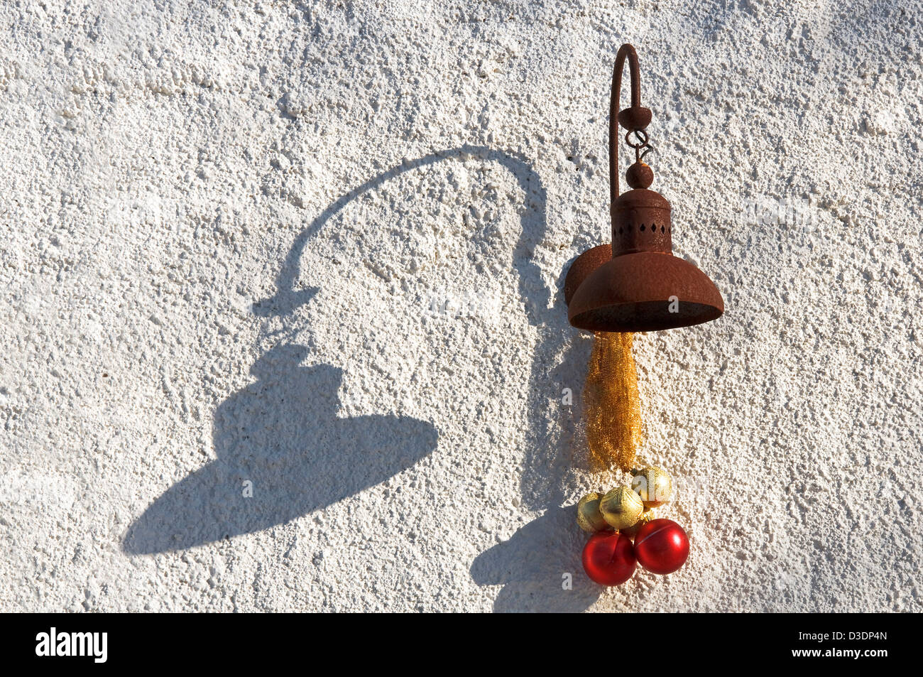 Rusty lamp with Christmas decoration and shadow on white exterior wall Stock Photo