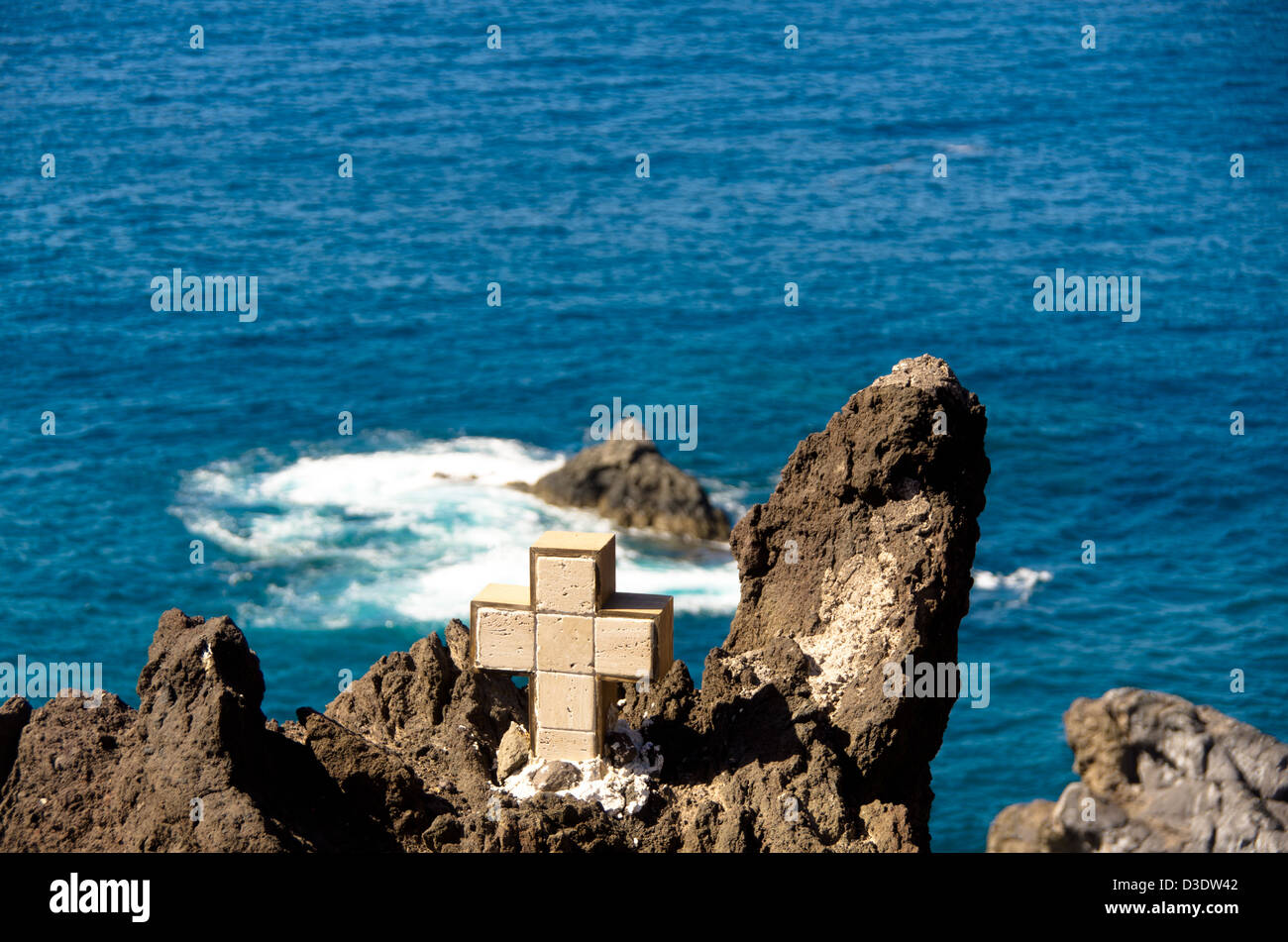 Cross overlooking a cliff with drop to the sea Stock Photo