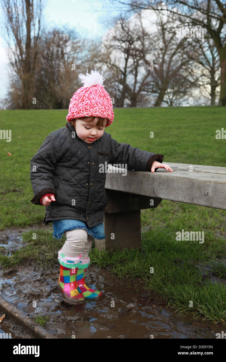 Toddler playing outdoors in the puddles. Stock Photo