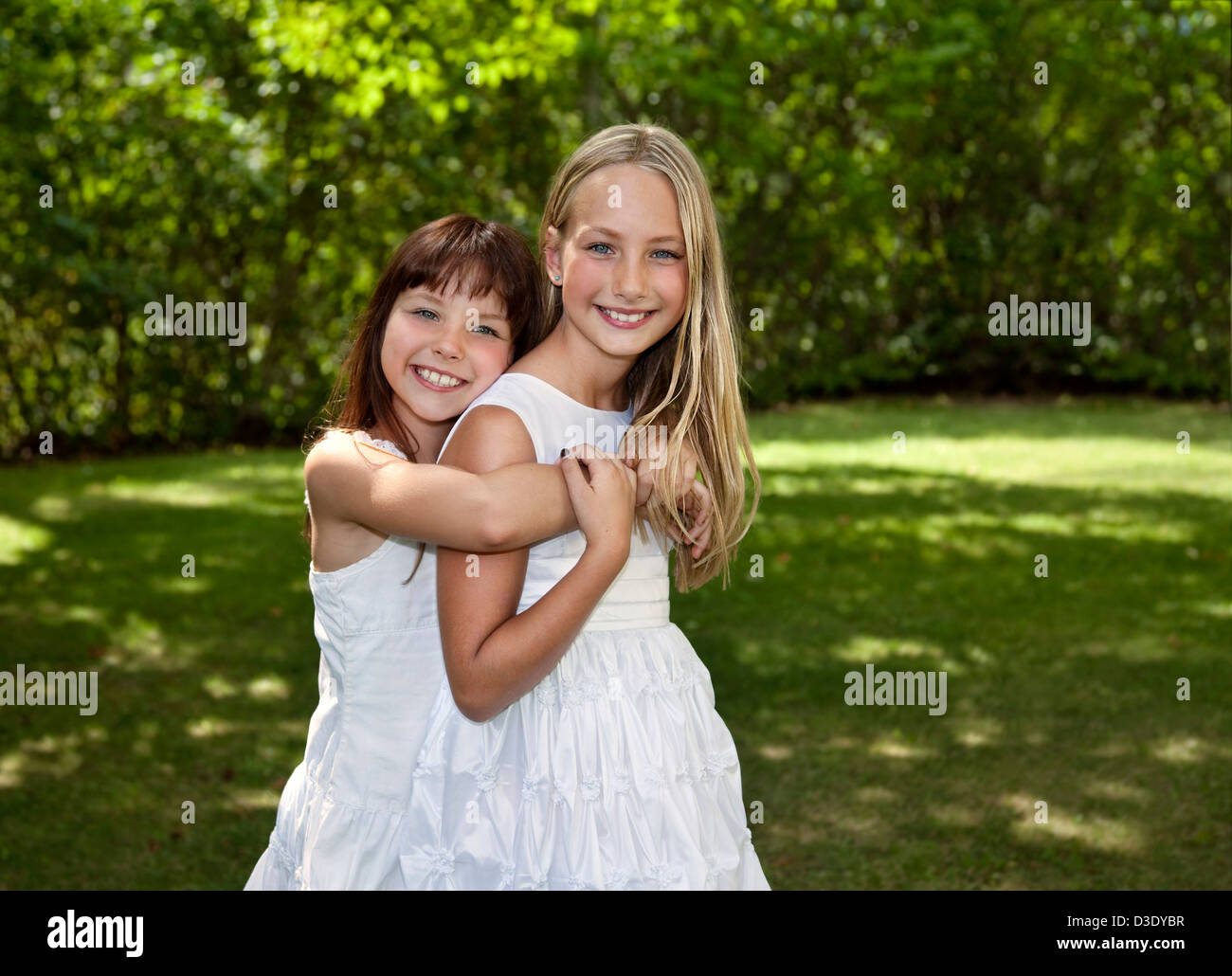 Outdoor photo of two young girls wearing white dresses with green ...