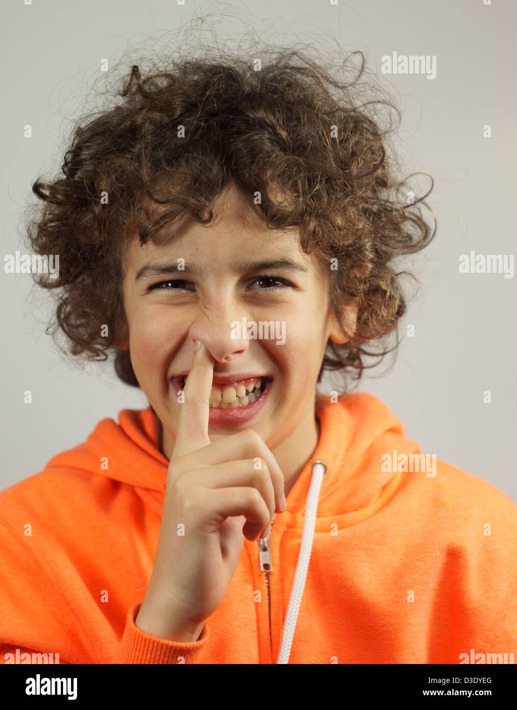 A young boy is picking his nose with a cheeky smile Stock Photo
