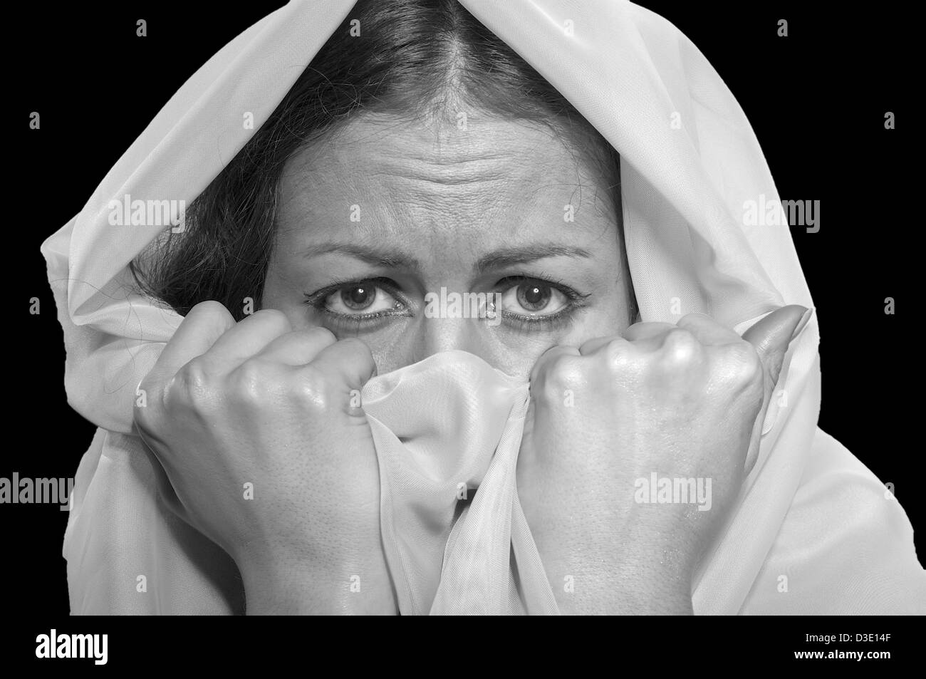 scared girl in white hijab isolated on black background, monochrome image Stock Photo
