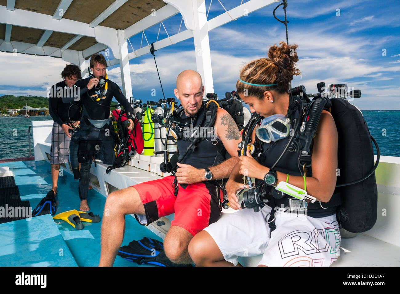 SCUBA divers prepare dive equipment on boat. Stock Photo
