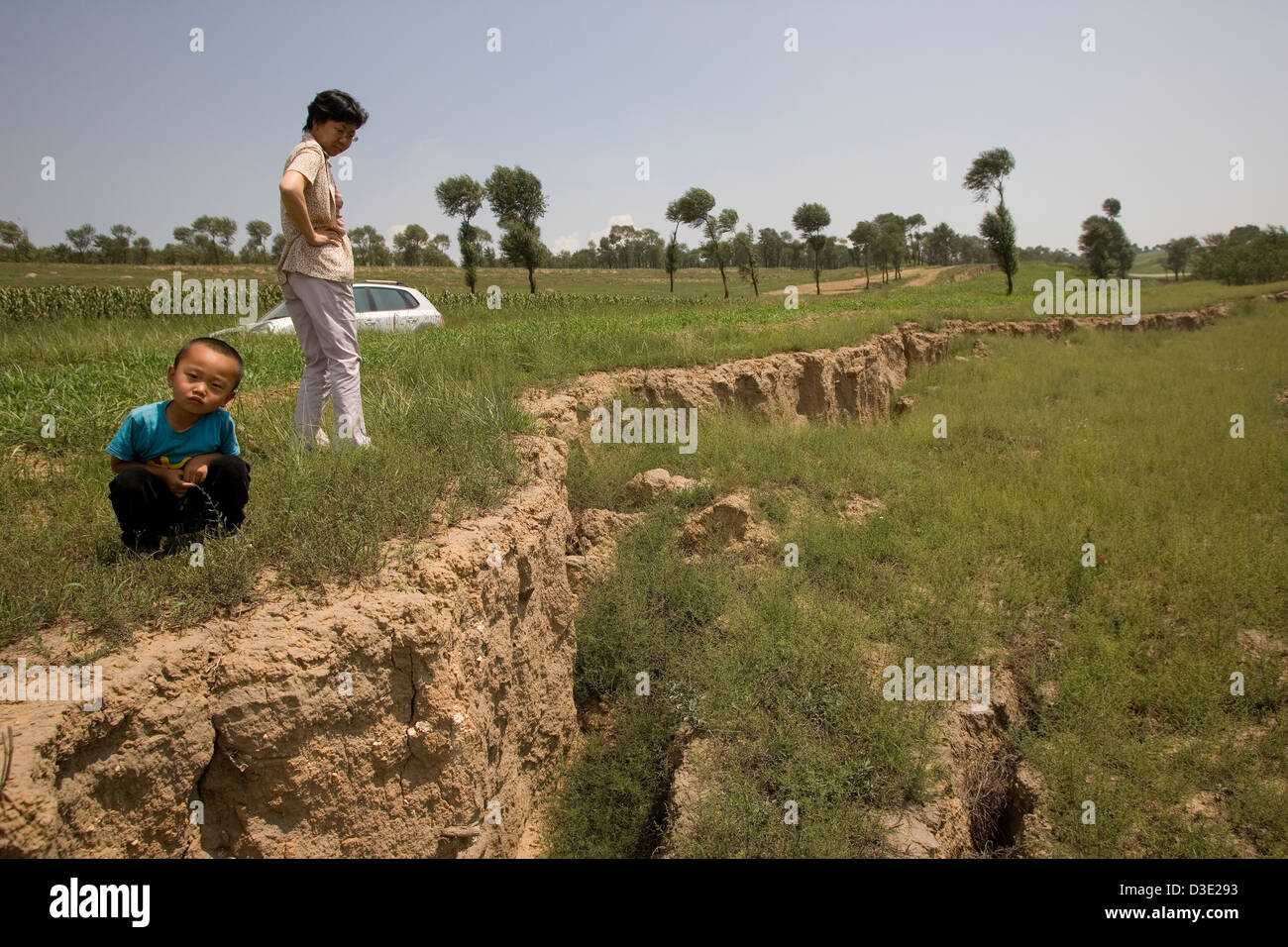 SHANG MAHUANGTOU VILLAGE, SHANXI PROVINCE, CHINA - AUGUST 2007:  A villager and her son inspect land subsidence caused by uncontrolled mining Stock Photo