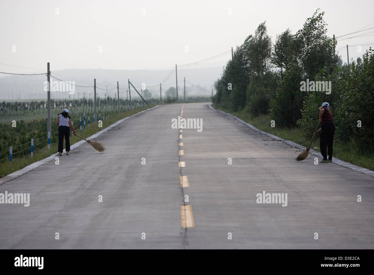 SHANXI PROVINCE, CHINA - AUGUST 2007:  Villagers sweep up coal dropped by passing coal trucks. Stock Photo