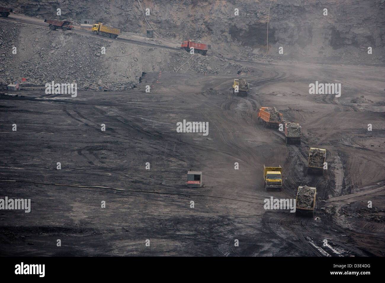 ORDOS, INNER MONGOLIA, CHINA - AUGUST 2007: A procession of 50 ton trucks are loaded with overburden on their way to a spoil heap at a new open cast mine near Ordos. Stock Photo