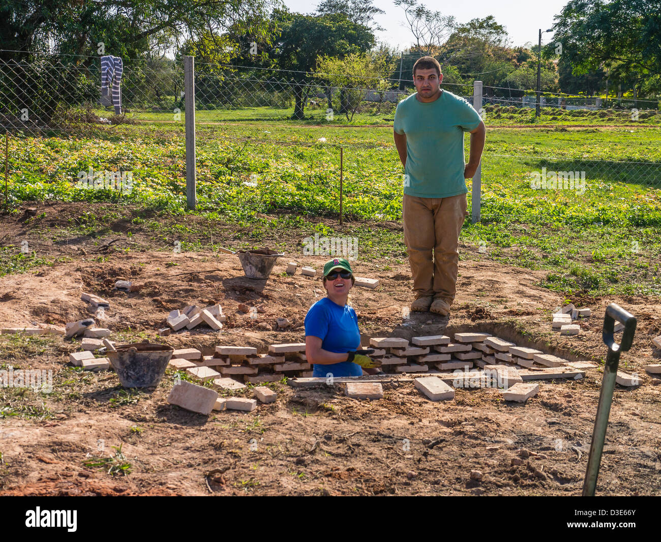 Two international volunteers help build a house for the needy sponsored by Habitat for Humanity Paraguay. Stock Photo