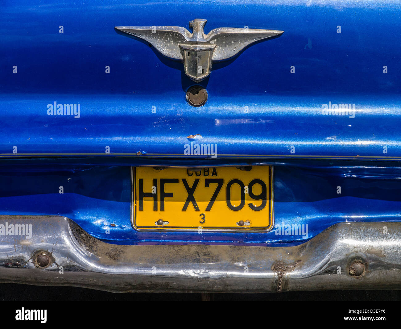 The rear end of a blue 1950s era Plymouth with yellow license plate in