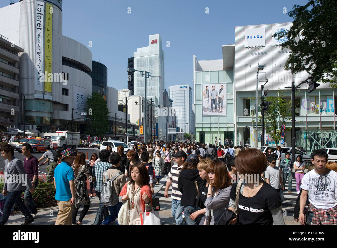 Young shoppers crowd upscale Shibuya district at intersection of Omotesando-dori and Meiji-dori streets on sunny day in Tokyo. Stock Photo