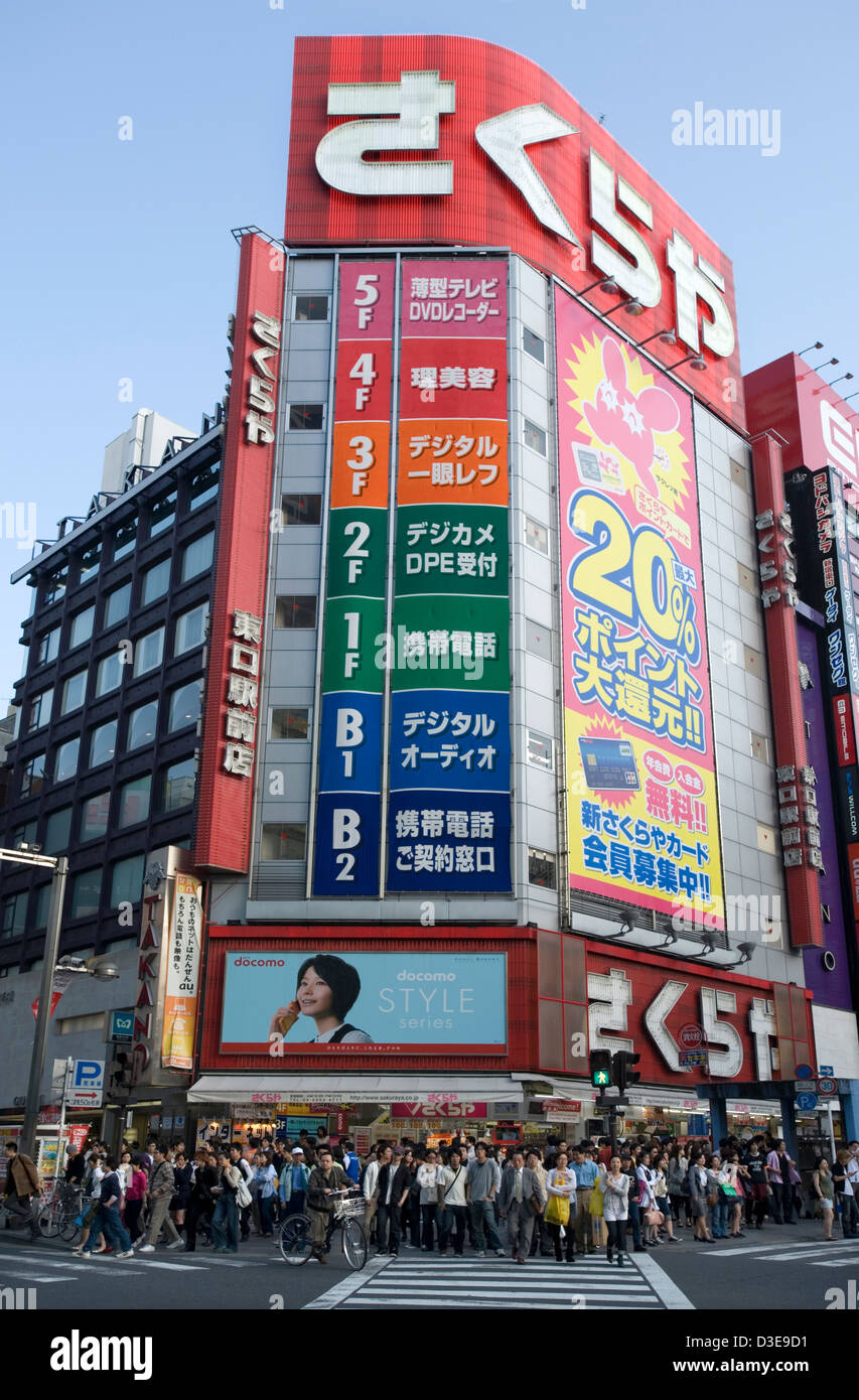 Shoppers waiting to cross a busy street in the shopping and entertainment district of East Shinjuku, Tokyo. Stock Photo