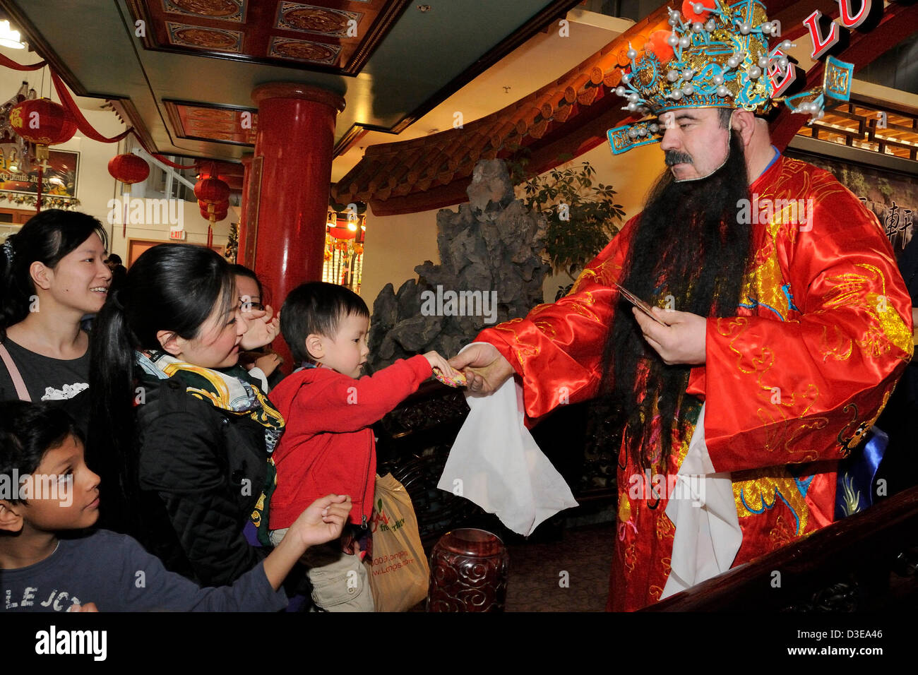 February 16, 2013. Toronto, Canada. Staff at Pacific Mall dressed up as Chinese God of Wealth - Tsai Shen Yeh, money god, handing out red envelops to children and shoppers as good luck and fortune celebrating the Chinese New Year. In picture, 3 year old Brendan Chan reaches out for the red envelope.  (DCP/N8N) Stock Photo