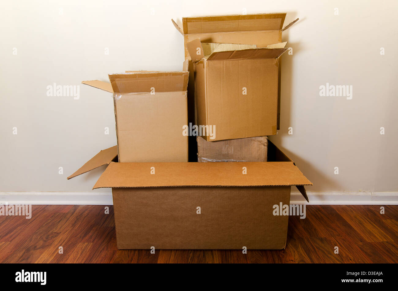 Moving day with empty cardboard boxes on hardwood floor. Stock Photo