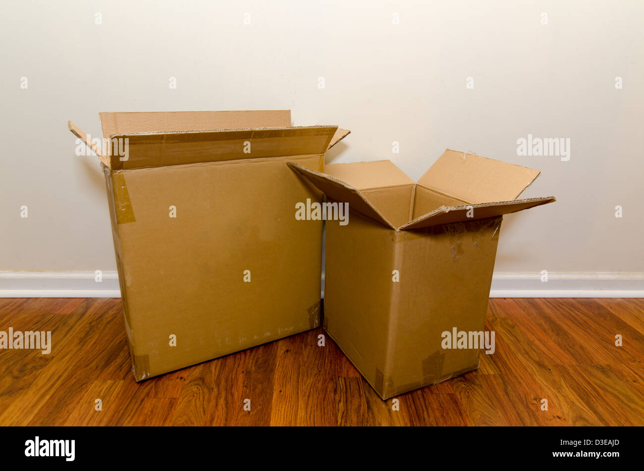 Moving day with empty cardboard boxes on hardwood floor. Stock Photo