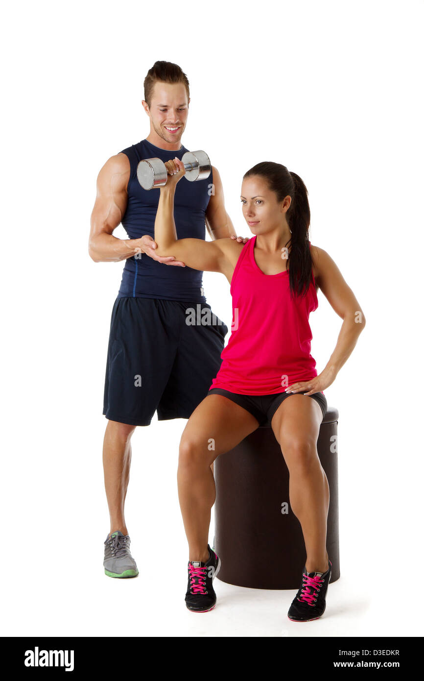Personal trainer assists beautiful woman lifting dumbbell Stock Photo ...