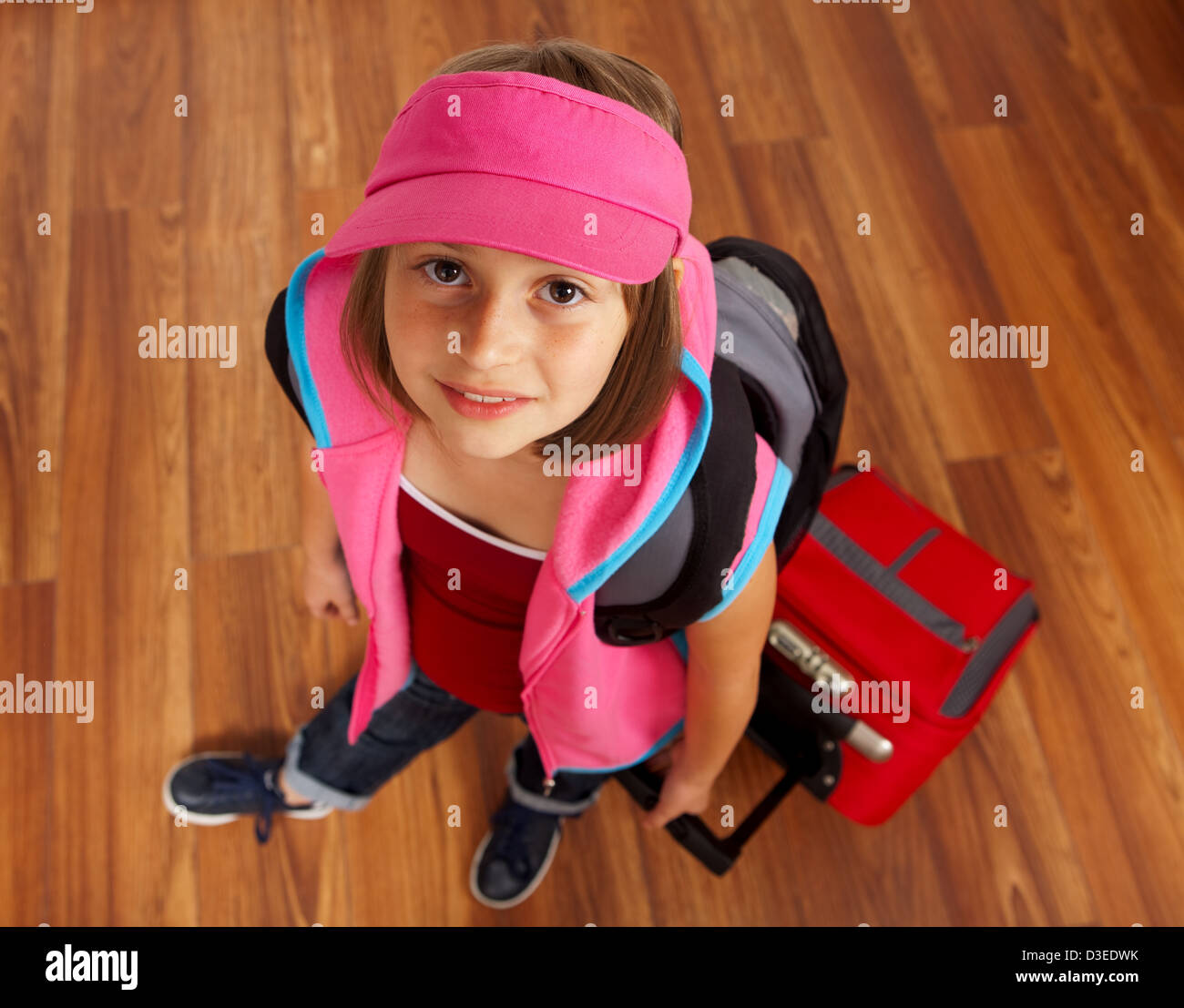 Little girl ready to travel, carrying red luggage Stock Photo