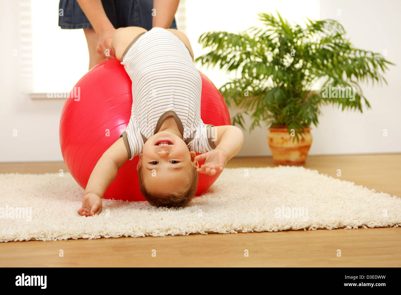 Baby boy playing on big red ball Stock Photo