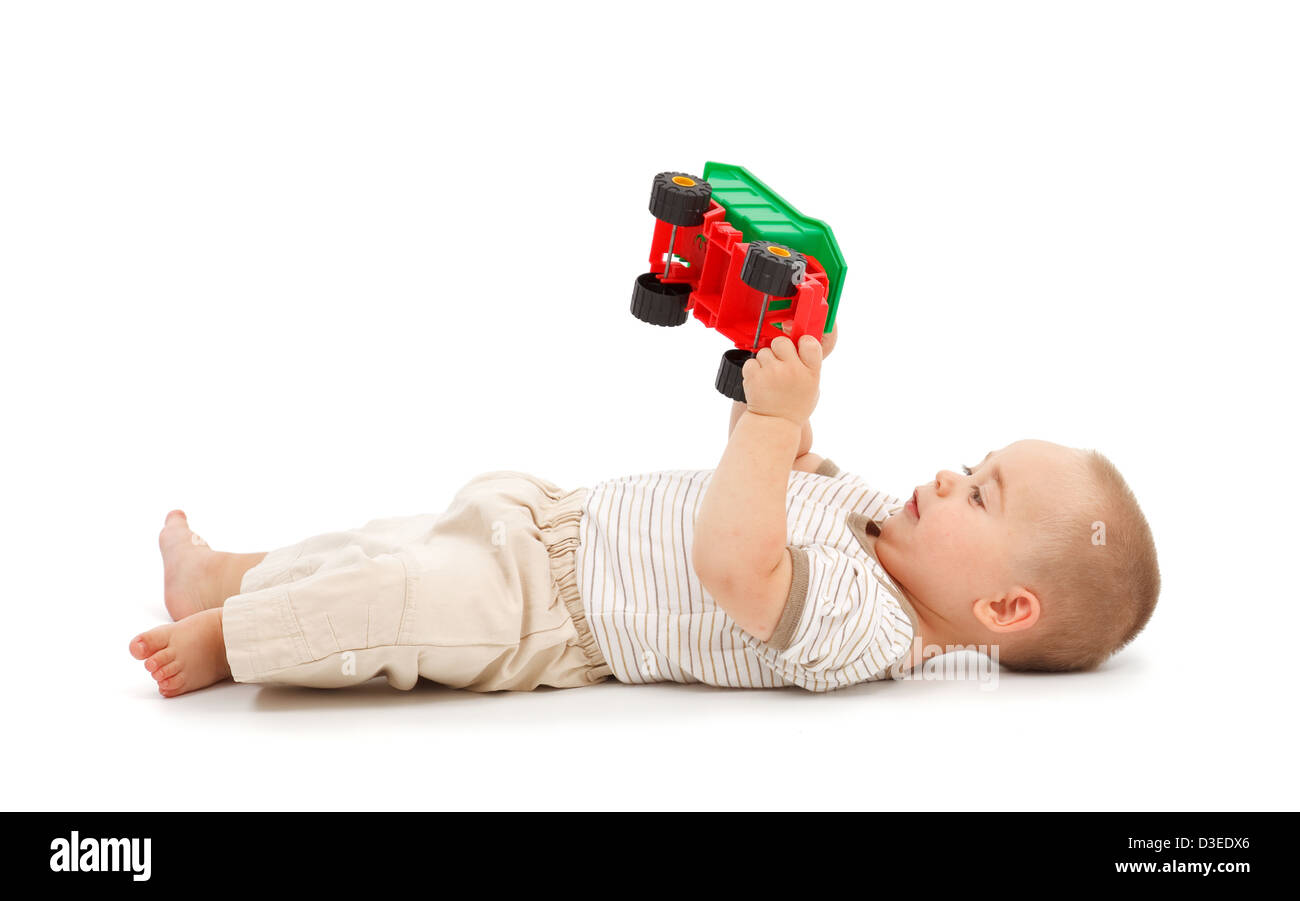 Little boy lying on back and playing with plastic toy car Stock Photo