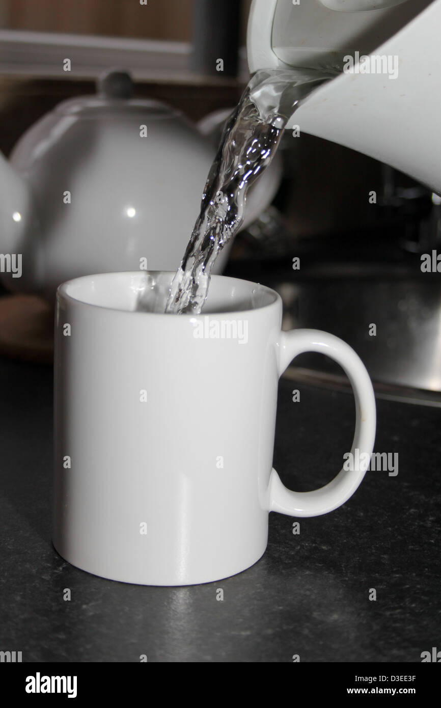 boiling water being poured from a kettle into a white mug Stock Photo
