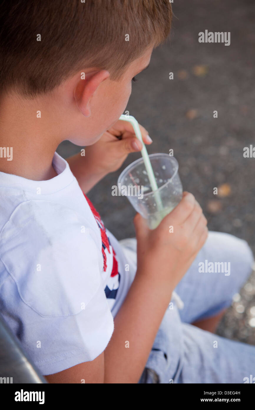 Boy drinking a lemonade slush outdoors in a summer afternoon. Stock Photo