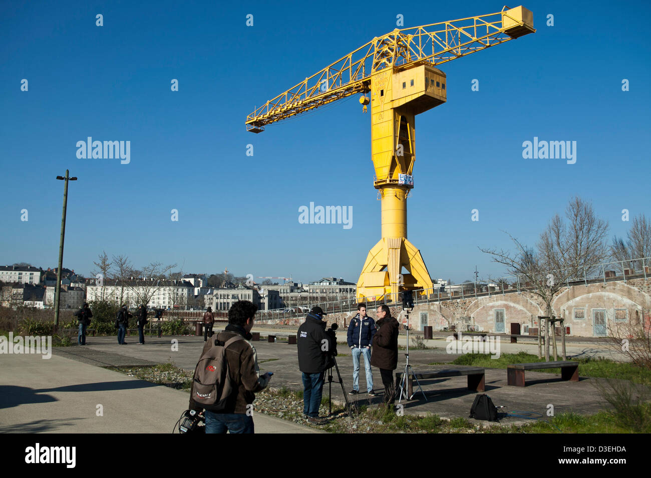 Members of the media are seen at the foot  of a 40 metre high shipyard crane in Nantes, France, 18 February 2013. Serge Charnay, 43, climbed up, and remains in, the crane on 16 February to protest a court decision denying him access to his son. Stock Photo