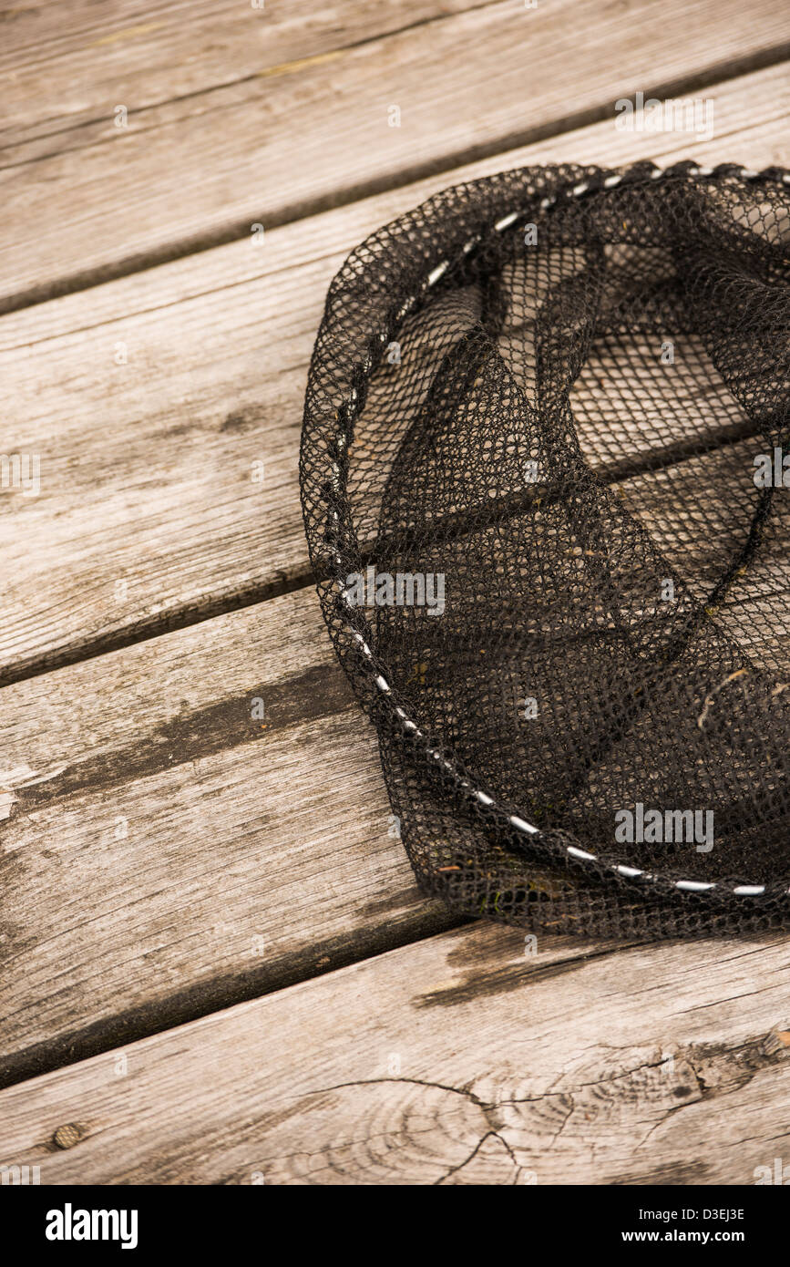 Closeup of fishing net lying on wooden deck of jetty Stock Photo