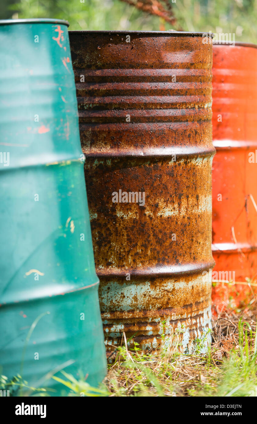 Rusty oil barrels with different colors standing in nature and being a threat to the environment Stock Photo