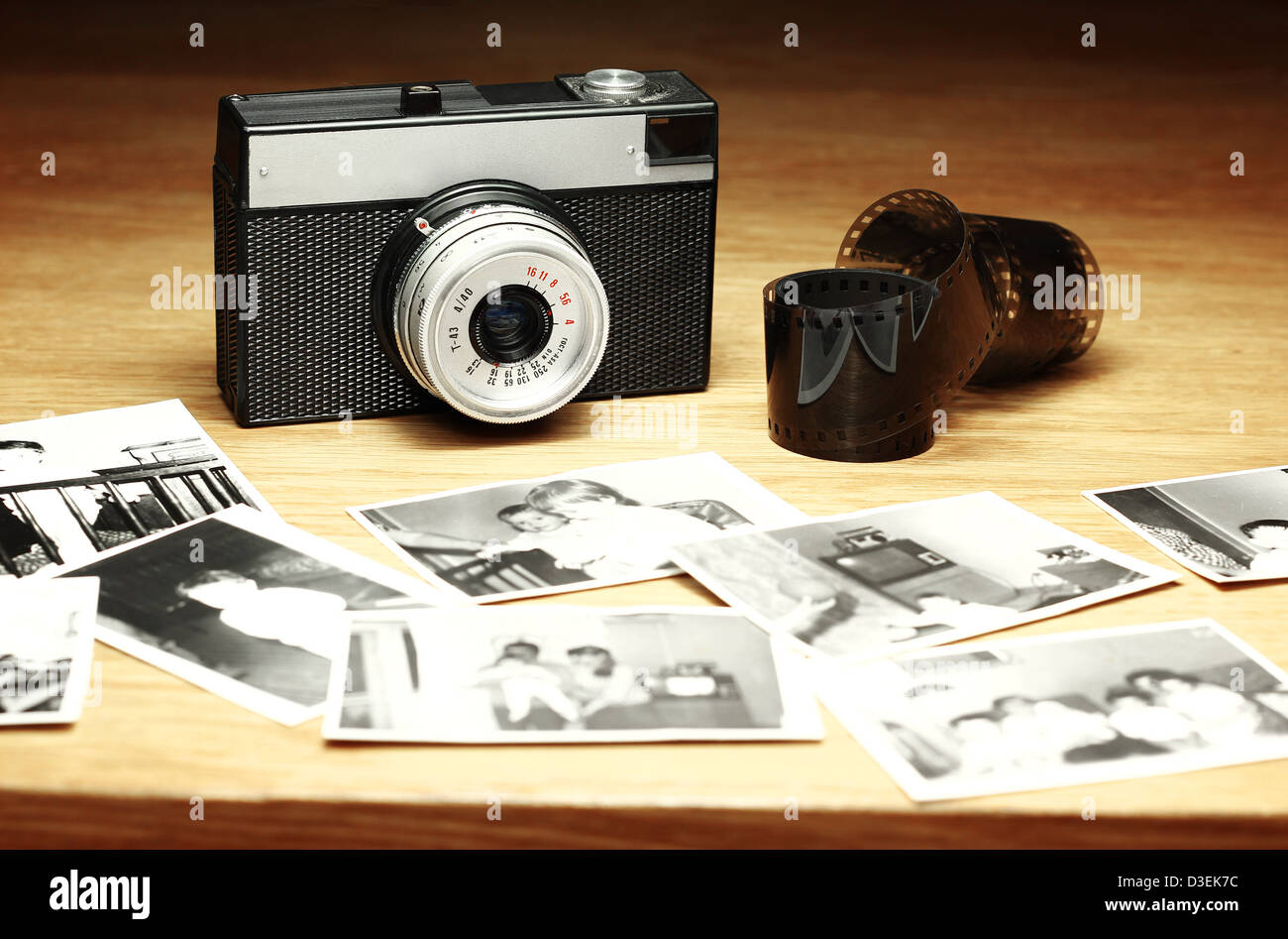 Old camera next to film and out of focus black and white photographs Stock Photo