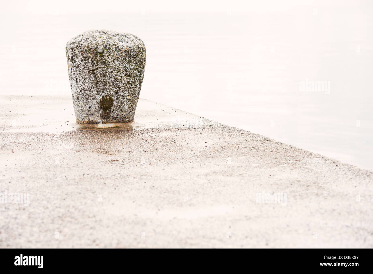 Tranquil scene of empty dock with stone bollard and calm sea Stock Photo