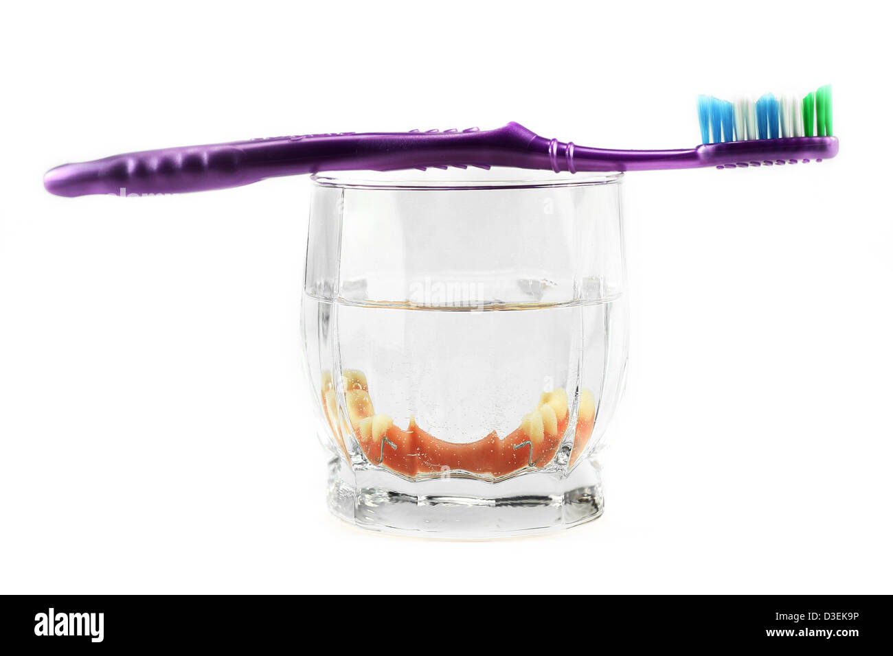 Partial denture inside glass with toothbrush on the top, isolated on