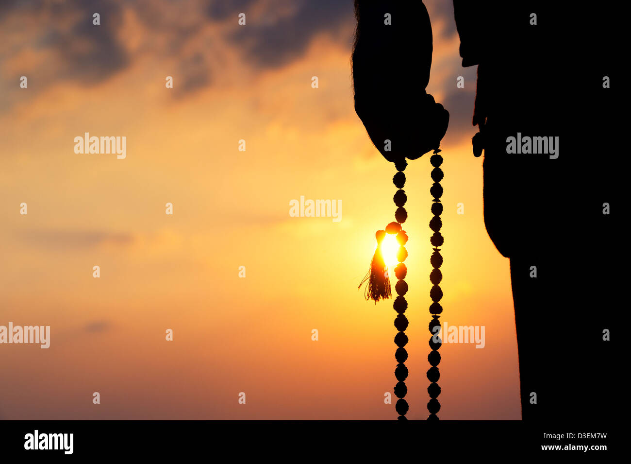 Mans hand holding Indian Rudraksha / Japa Mala prayer beads. Silhouette Stock Photo