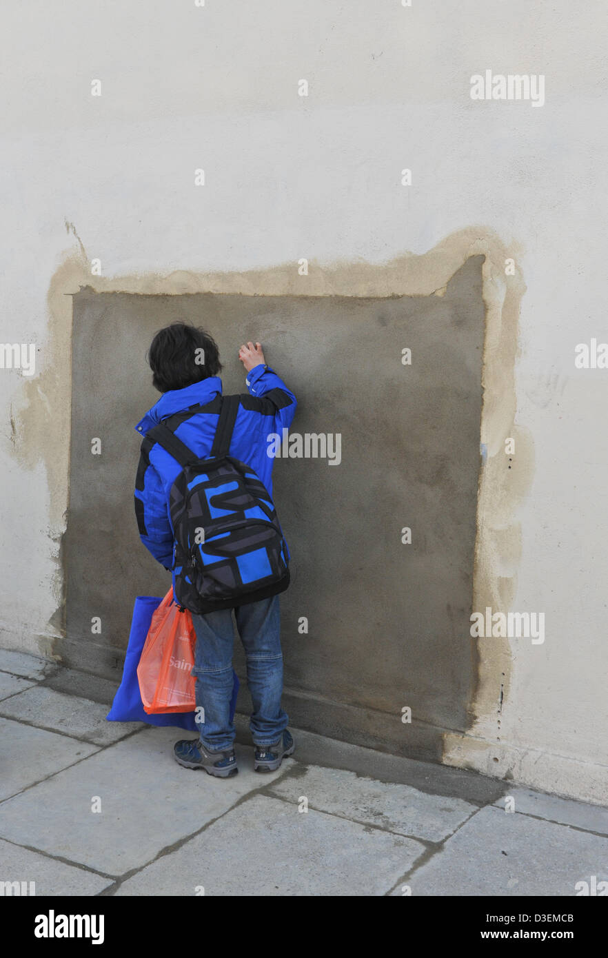 Wood Green, London, UK. 18th February 2013. A boy looks at the cemented up hole where the Banksy artwork was.The Banksy picture of a boy with Union Jack bunting has been removed and is now on sale on an American auction site and is estimated to be worth $500,000-$700,000. Credit: Matthew Chattle/Alamy Live News Stock Photo
