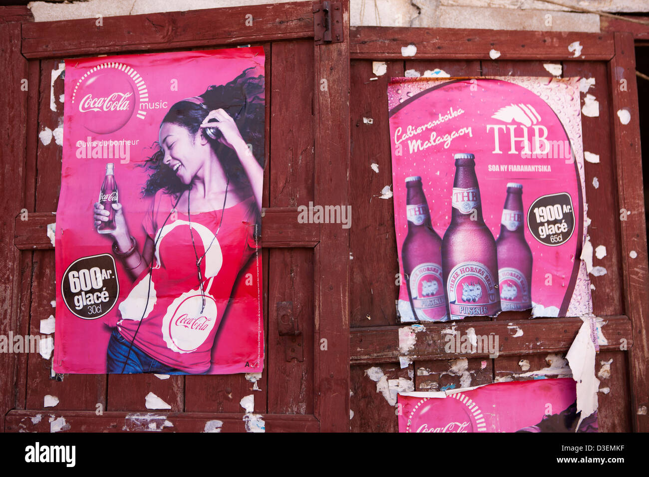 Madagascar, Ambositra, Sandrandahy sun-bleached Malagasy language coca cola and THB Three Horses beer posters on door Stock Photo
