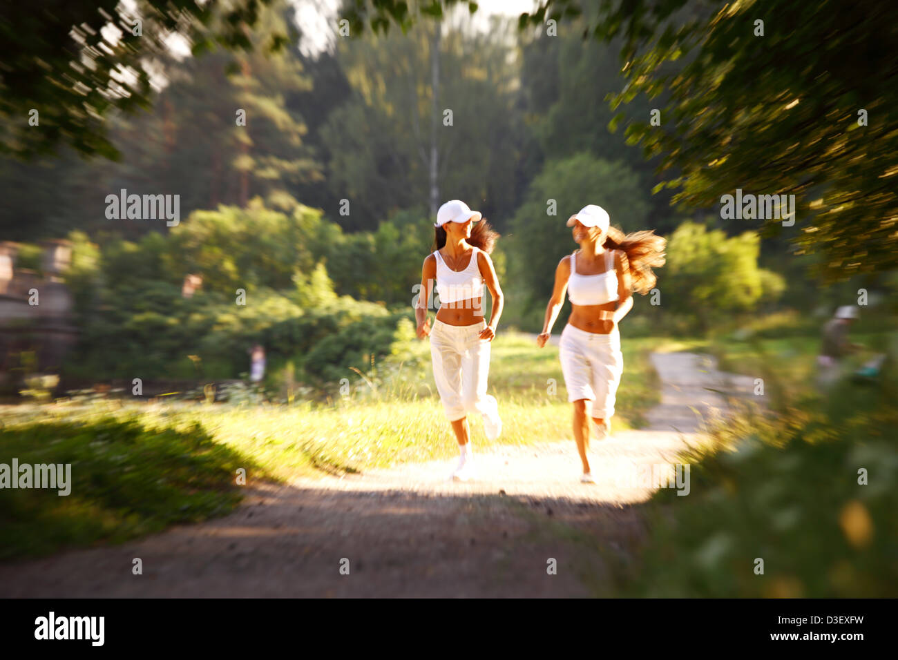 women run by sunny park alley Stock Photo Alamy