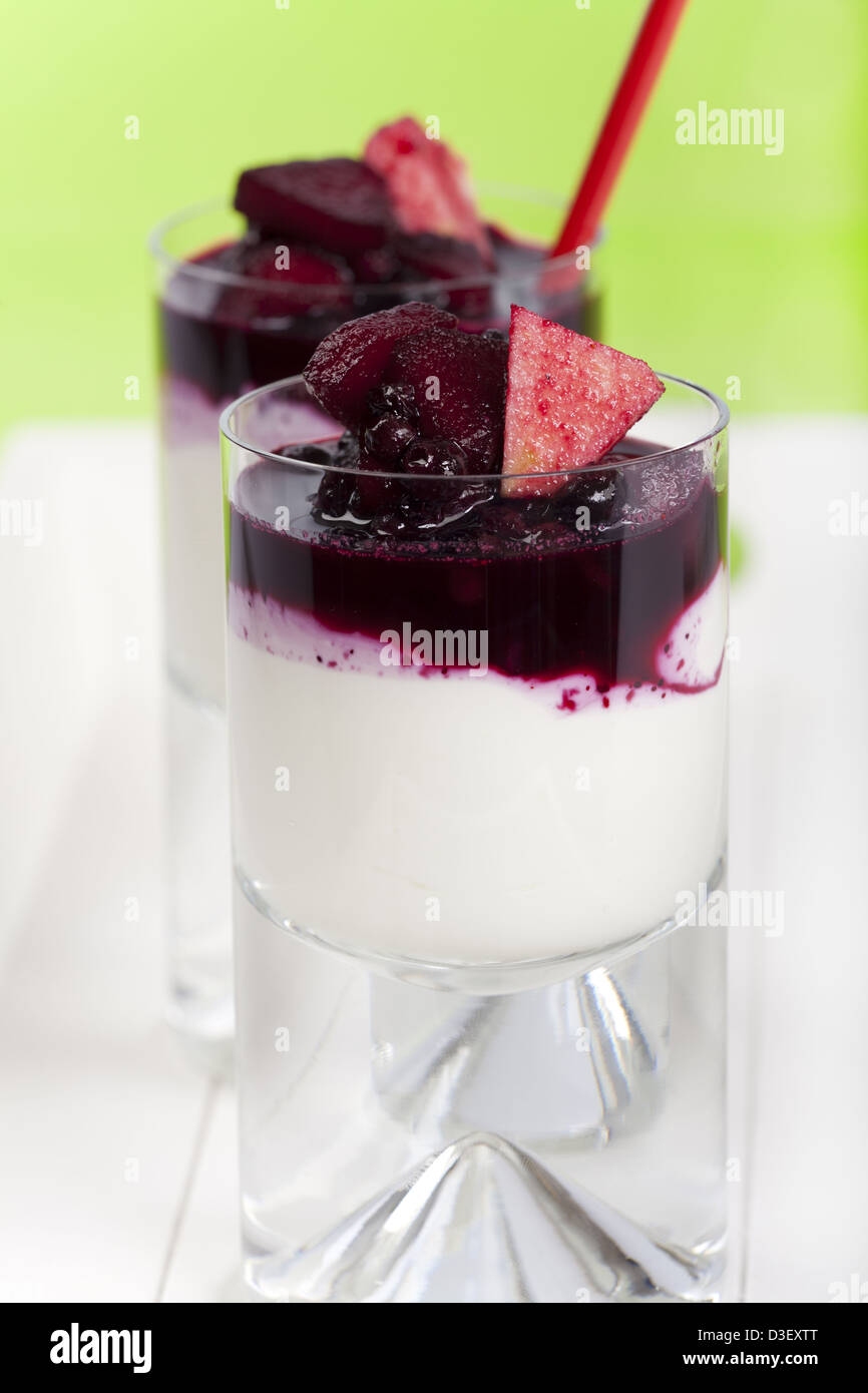 Two glasses of homemade yogurt curd dessert with blueberries and apple slices on a green background Stock Photo