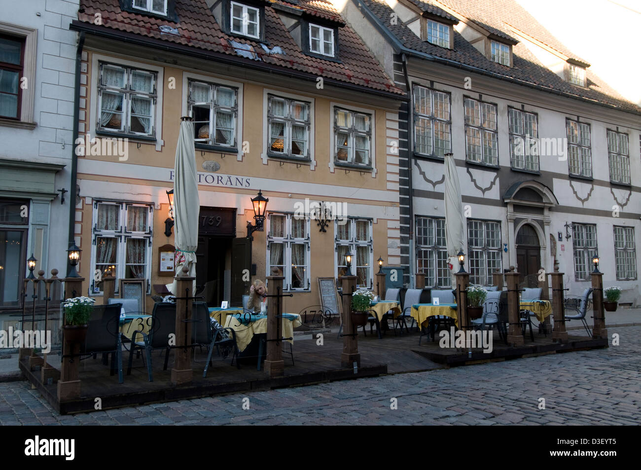 At dusk at one of the many restaurants with platform seating in the narrow cobblestone streets in Riga Old Town,Riga,Latvia, Baltic States Stock Photo