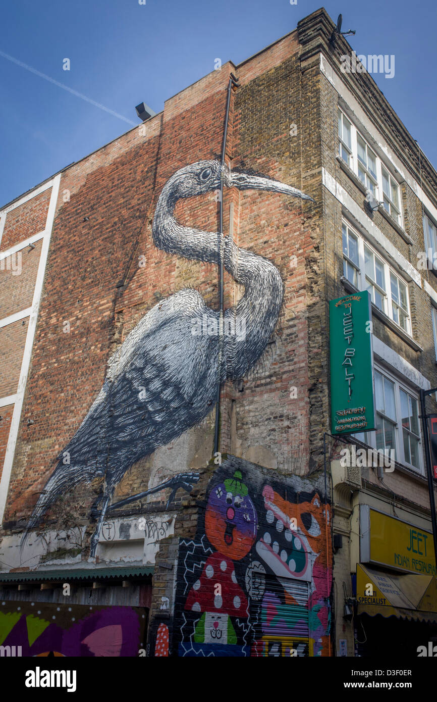 The image of the artwork called Big Bird by the Belgian artist Roa is seen on the side of a Balti restaurant in Hanbury Street, off Brick Lane, East London. Painted in 8 hours onto Victorian brick, the work has become a known landmark on this and surrounding streets where little known artists as well as Roa and Banksy have adorned walls and doorways. ROA (born c. 1975) is the pseudonym of an anonymous graffiti artist from Ghent, Belgium who has created works on the streets of cities across Europe and the United States. Stock Photo