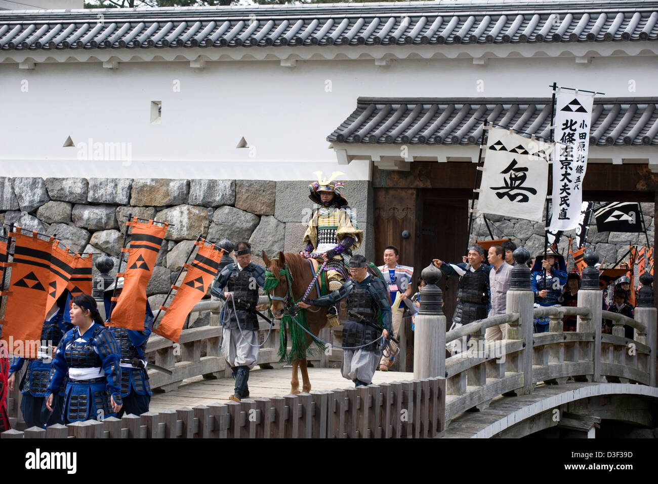 Samurai warriors wearing traditional armor crossing moat bridge at Akaganemon Gate during Odawara Hojo Godai Matsuri festival. Stock Photo