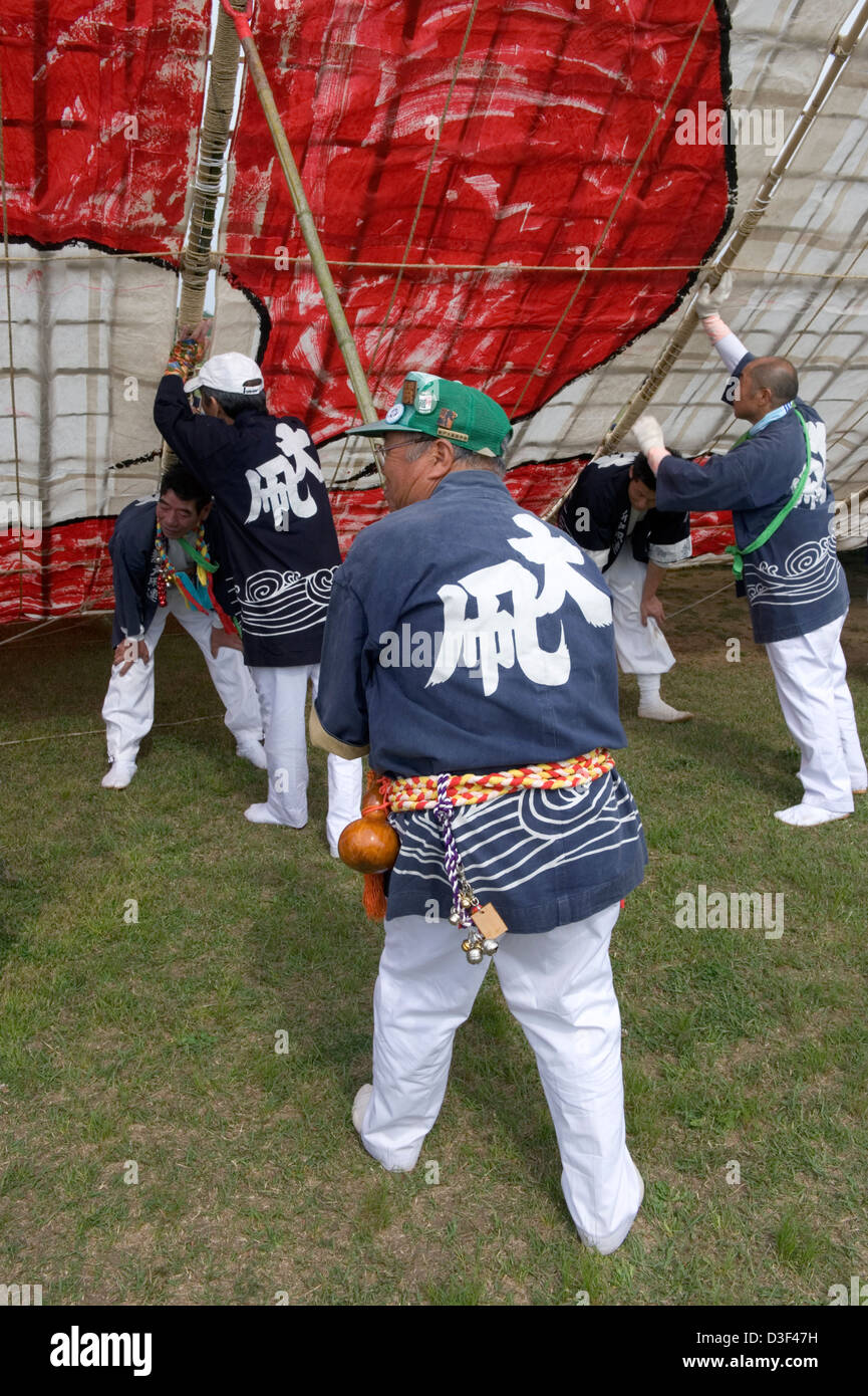 Team wearing happi coats hold up paper and bamboo kite for assembly at ...